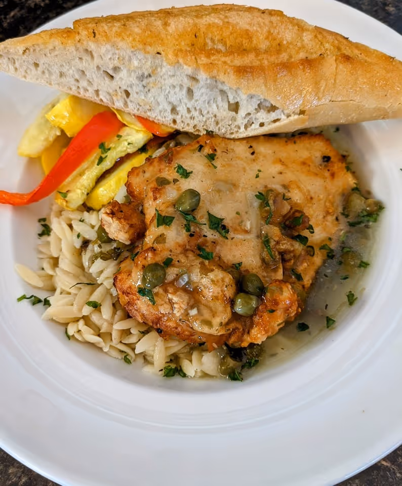 A plate of food with a piece of chicken and a piece of bread.