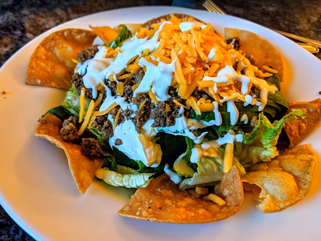 A plate of food with lettuce, cheese, and chips.