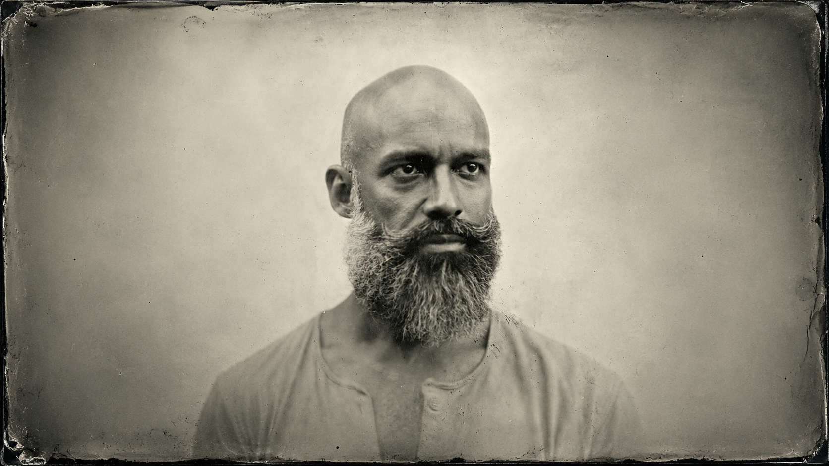 A moody, mysterious image of man in a beard wearing a hat