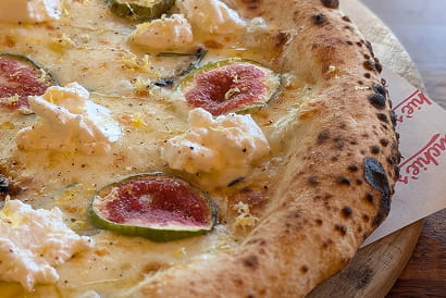 Neapolitan-style pizza topped with fresh figs, creamy ricotta and a golden, charred crust.