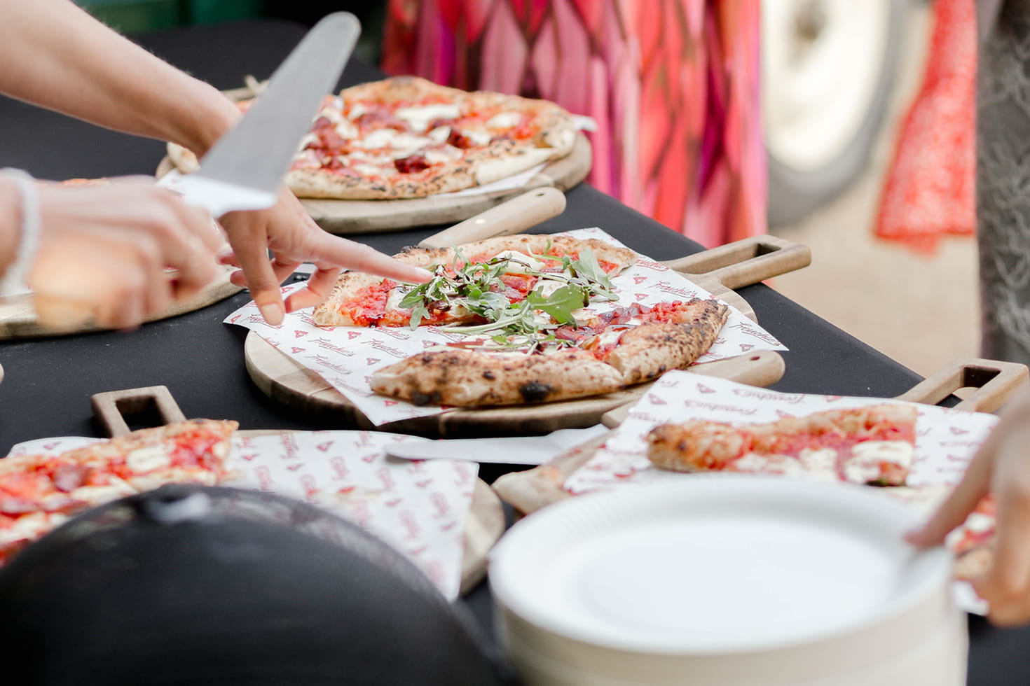Guests sharing freshly baked Neapolitan pizzas served on wooden boards at an event.