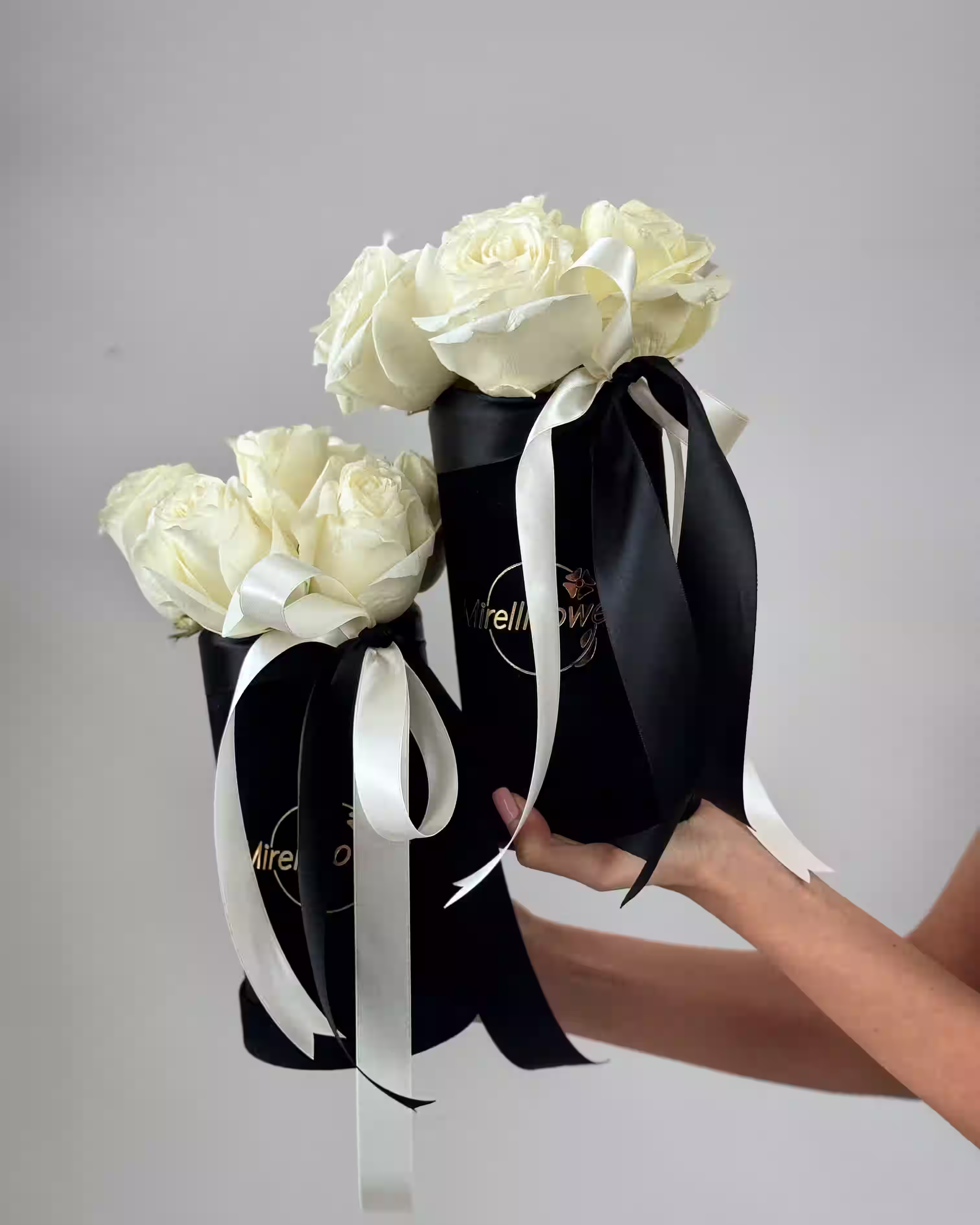 Dva crna flower boxa napunjena bijelim cvijećem.