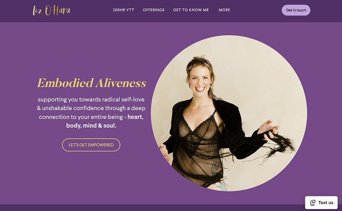 Smiling woman wearing a black lace top with a sheer shawl, posing against a beige background inside a circular frame.