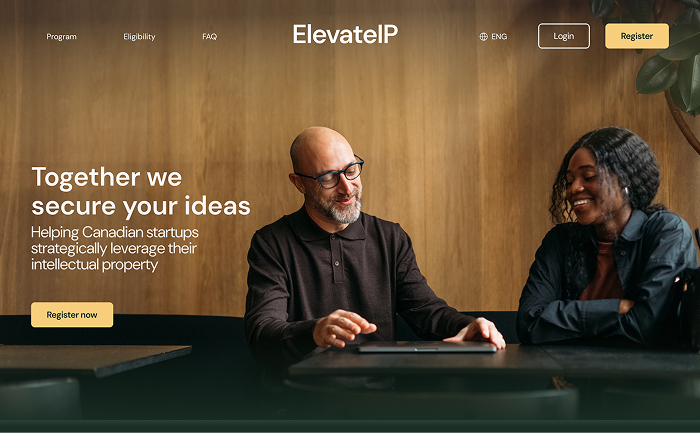 Two professionals, a bald man with glasses and a woman with curly hair, smiling and discussing at a table with a wooden background.