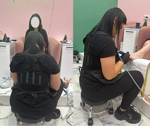 Femeie cu hanorac roșu și părul prins în coc, făcând un selfie în oglindă care arată din față și din spate un corector de postură negru purtat peste hanorac.