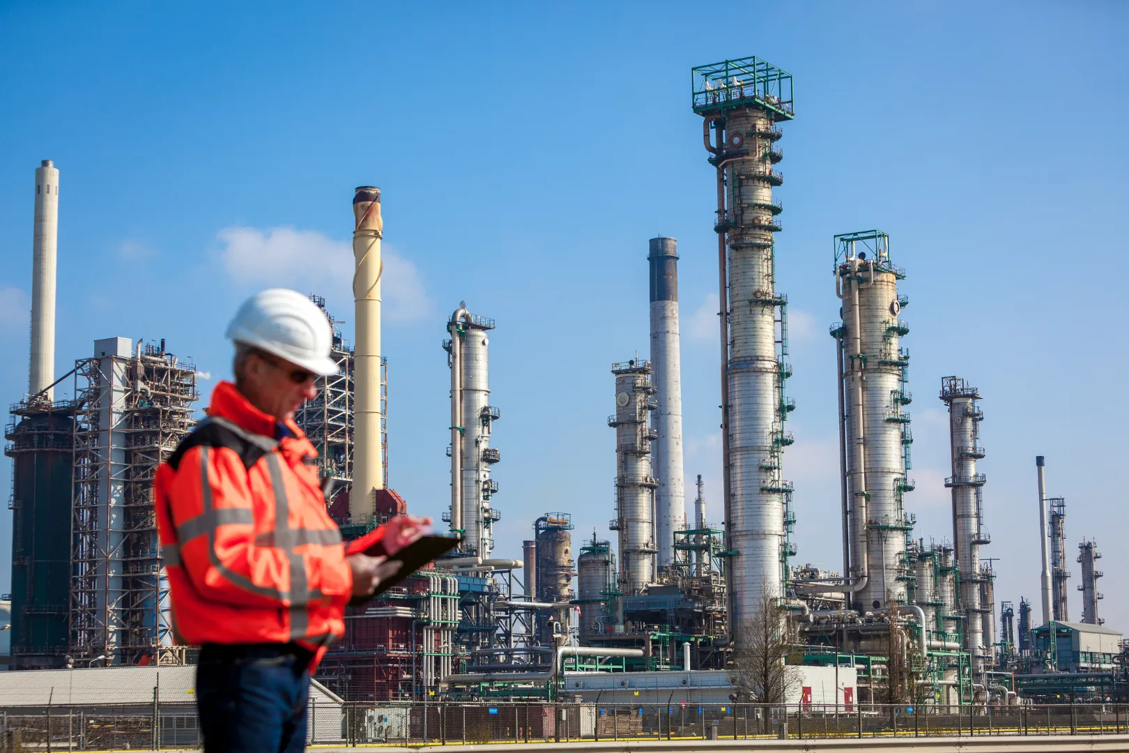 Mann mit roter Warnjacke steht vor Industriegelände