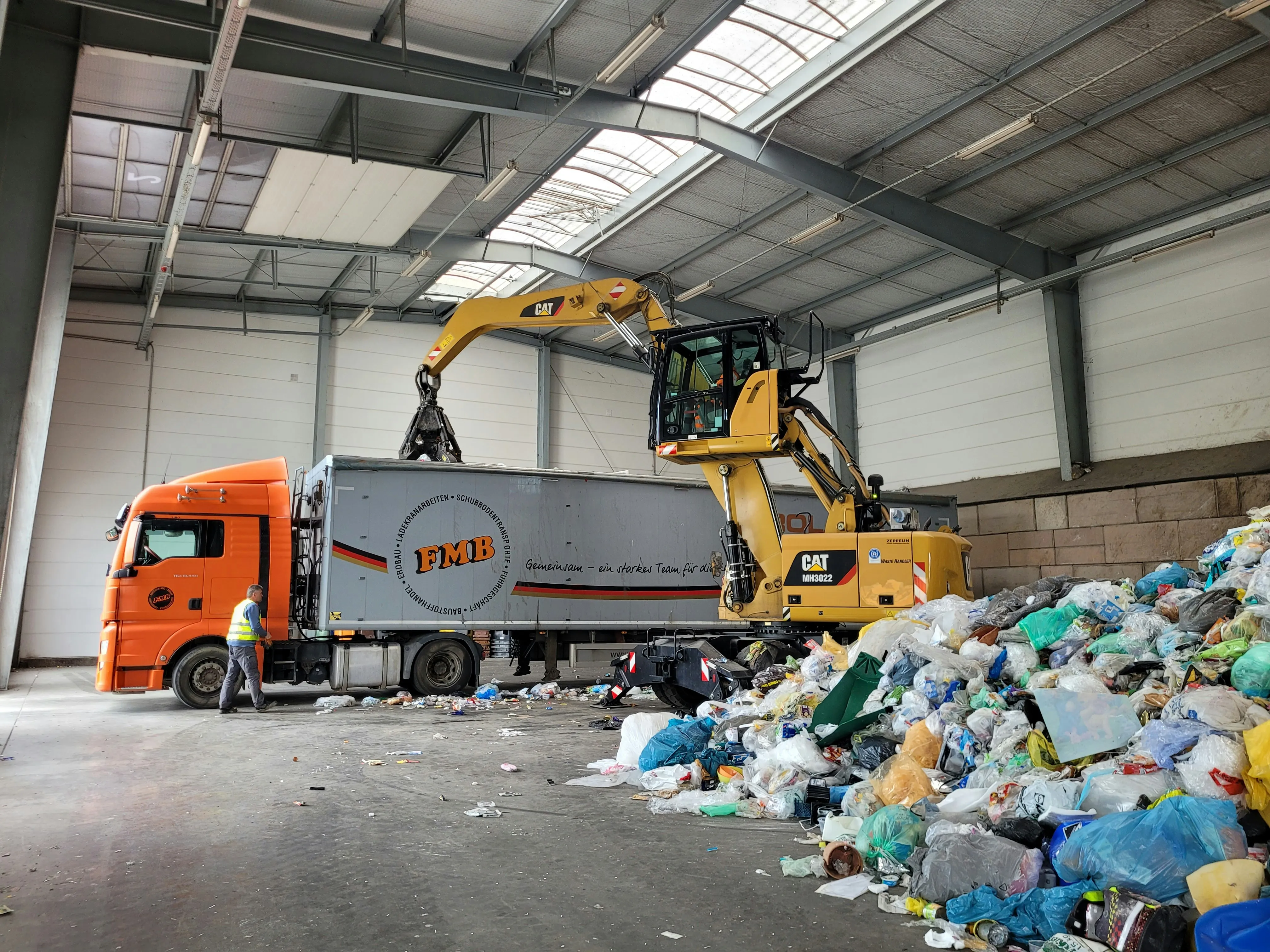 Fahrzeug lädt Müll in Lkw in großer Halle