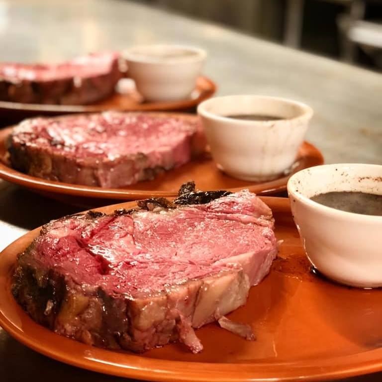 Three plates featuring succulent meat topped with rich sauce, arranged side by side on a dining table.