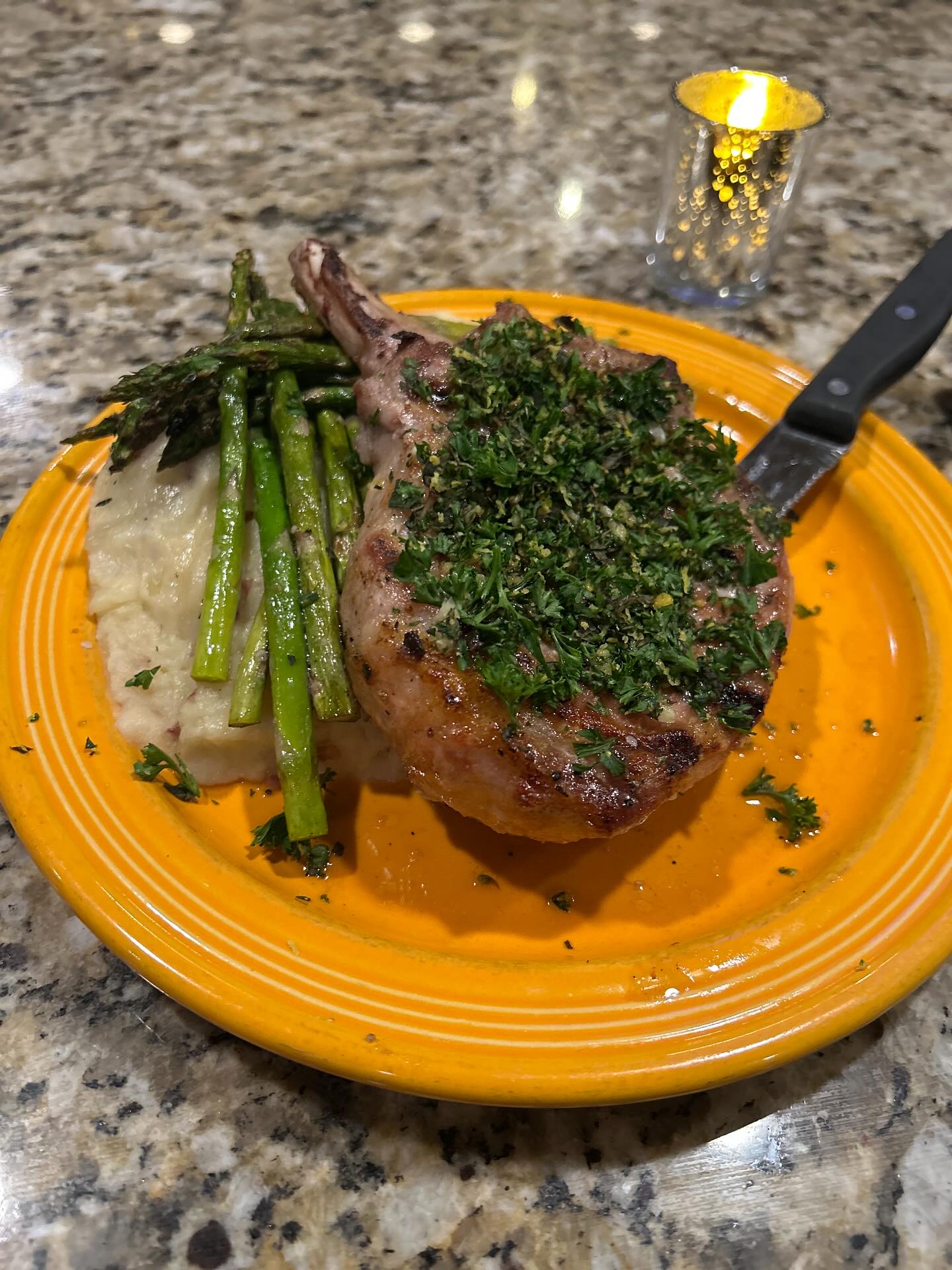 A plate featuring a roasted rib, asparagus, and creamy mashed potatoes.