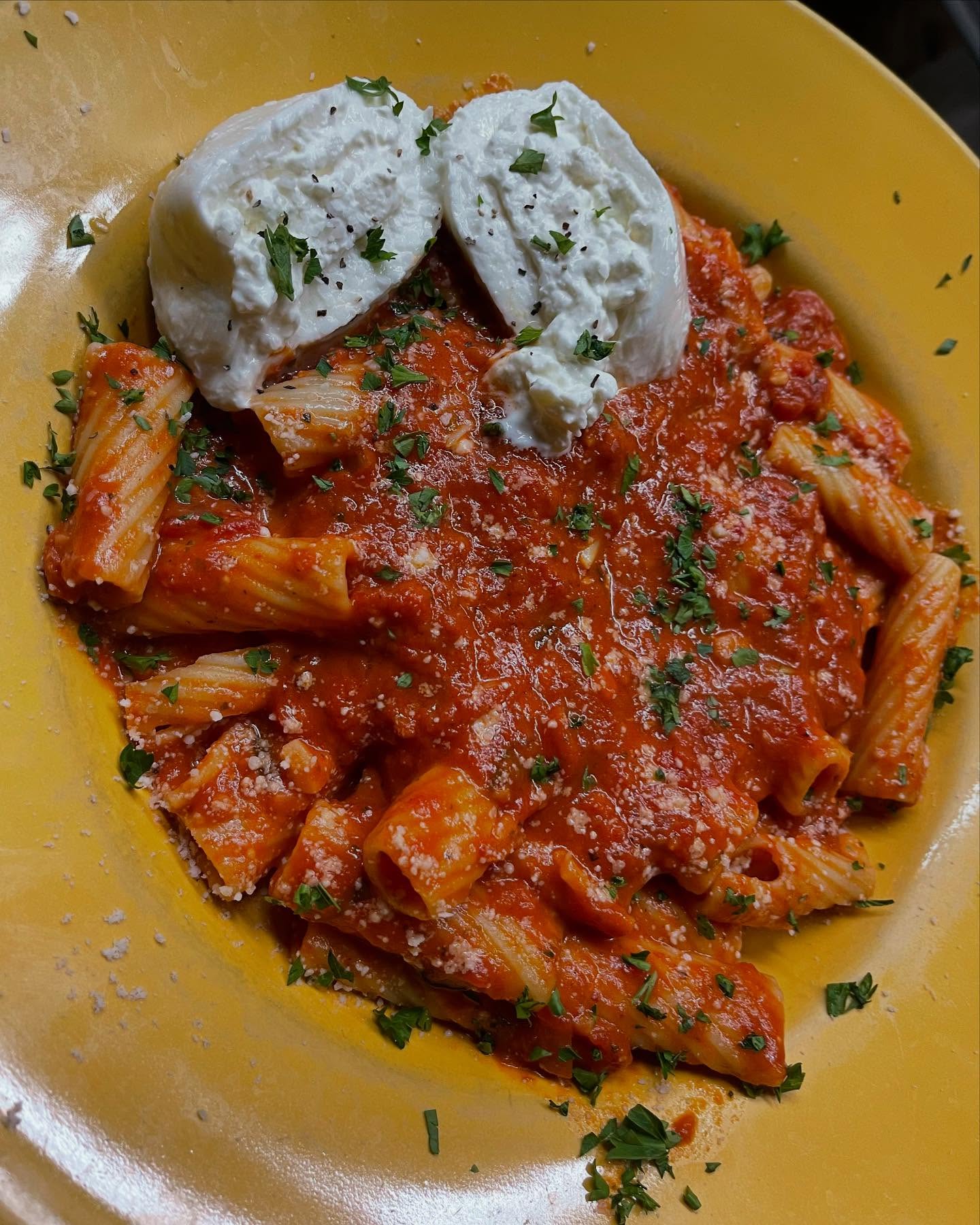 A plate of pasta topped with rich marinara sauce, garnished with fresh basil leaves.
