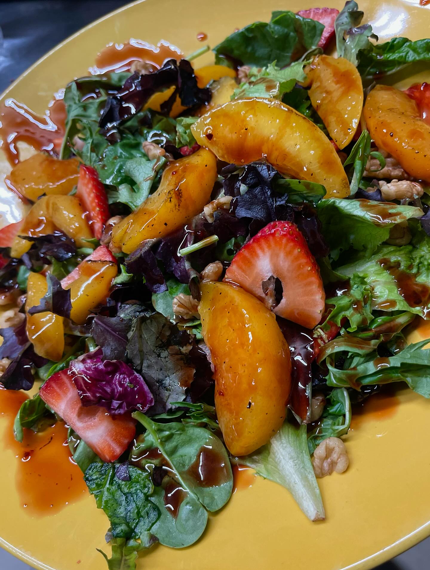 A plate featuring a colorful salad with strawberries and peaches.