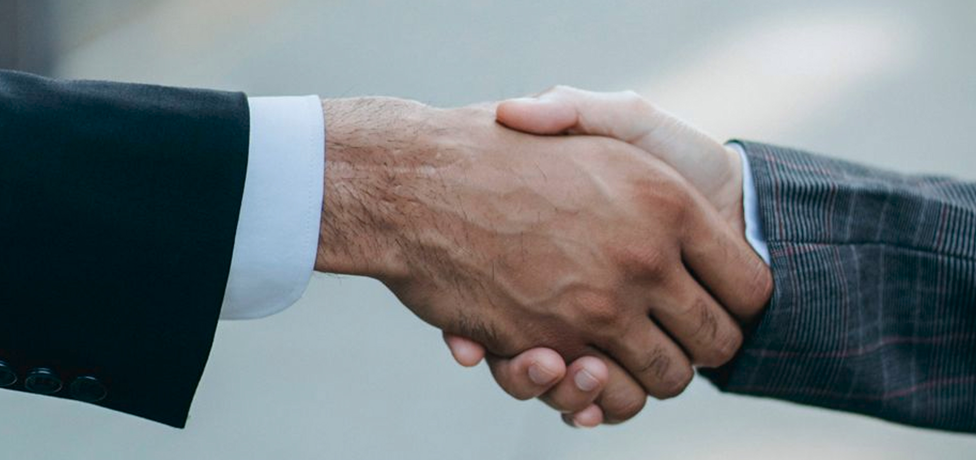 Apretón de manos entre dos personas con trajes formales.