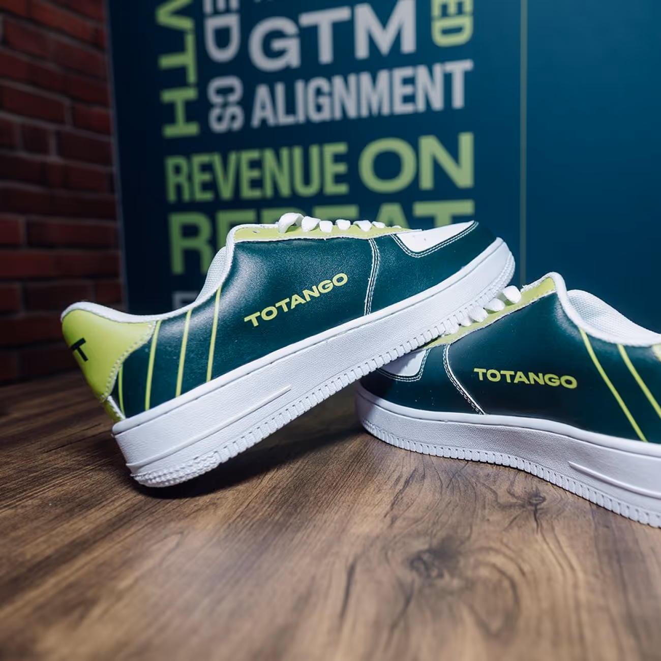 Pair of green and white sneakers with yellow 'TOTANGO' branding placed on a wooden surface.