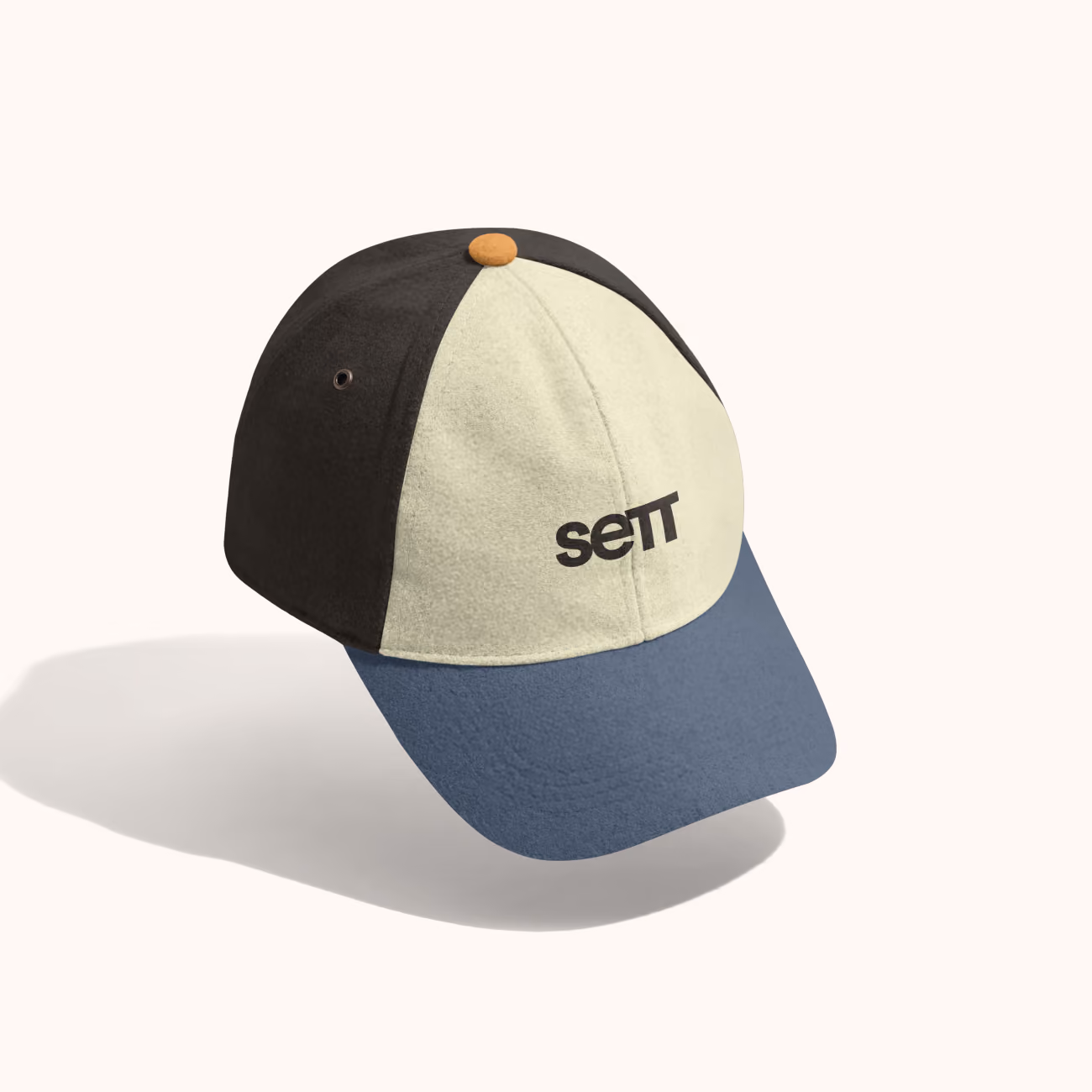 Color-blocked baseball cap with blue brim, cream front panel, black side panels, and text 'sett' on front.