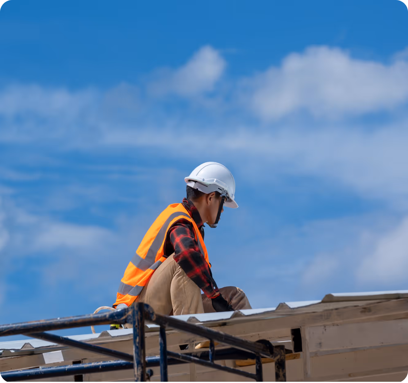 Ouvrier de construction portant un casque et un gilet orange sur un toit