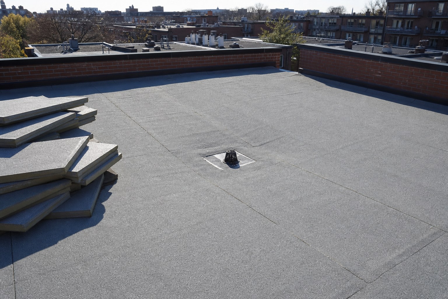 Toit plat de plex montréalais avec drain central et panneaux d'isolant biseautés servant à créer la pente.