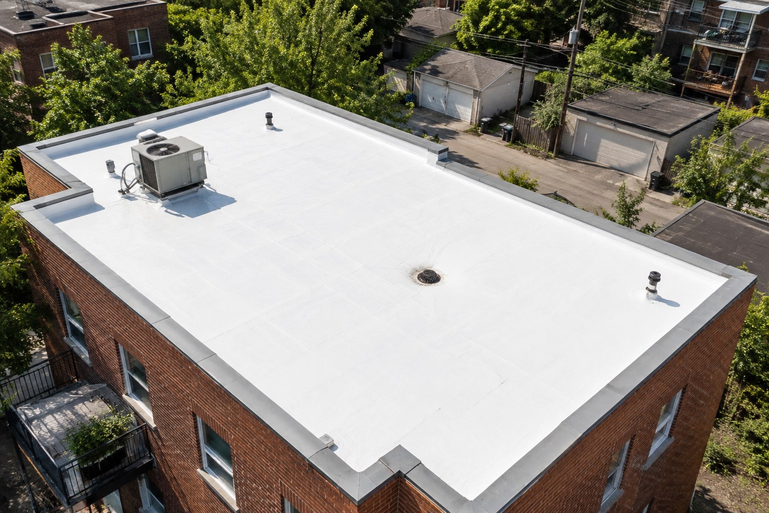 Toit plat de plex montréalais recouvert d'une membrane blanche réfléchissante, vu du dessus en plein soleil d'été.