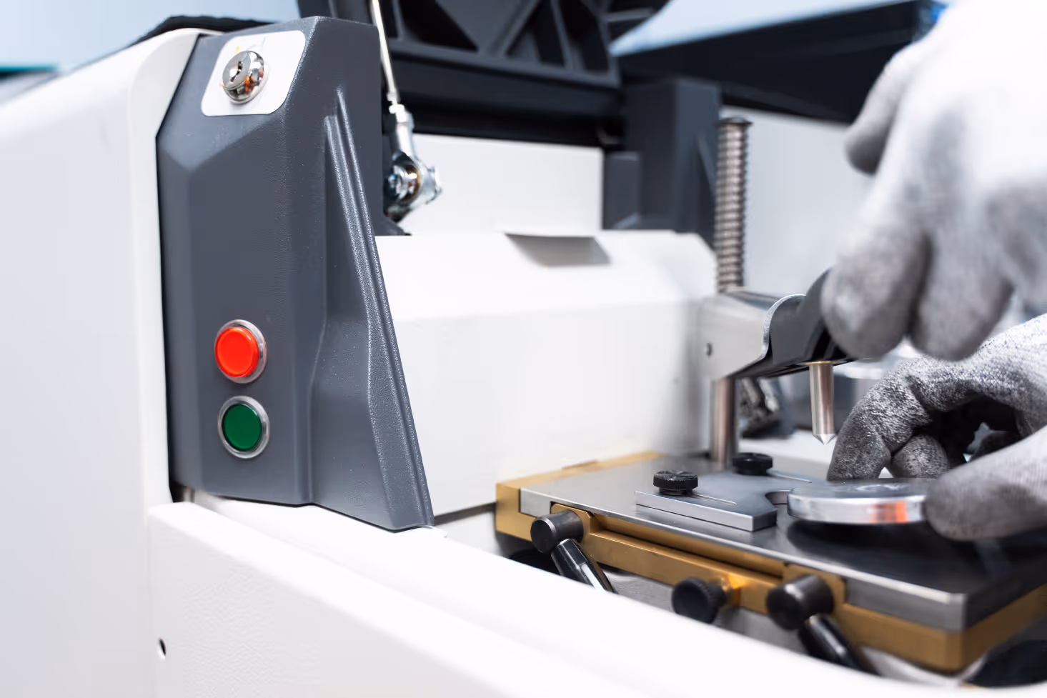 Close-up of gloved hands operating a precision measurement machine with red and green buttons.