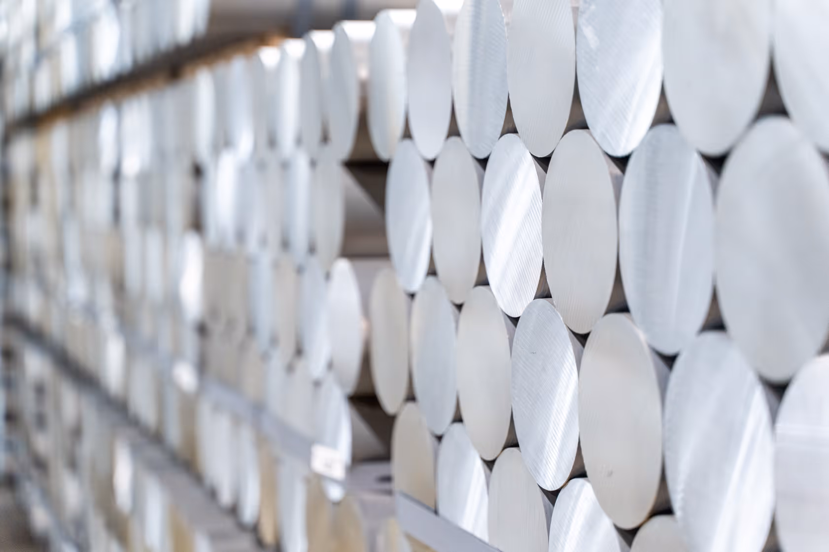 Close-up view of neatly stacked cylindrical metal rods with smooth, reflective ends.
