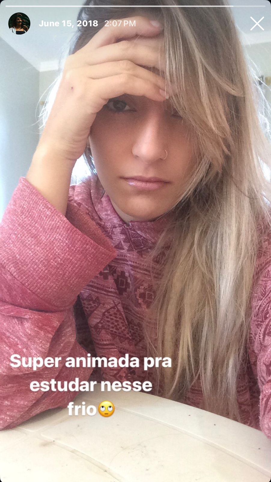 Daniella wrapped in a patterned shawl sitting in a green hammock, holding a mug and looking contemplative.