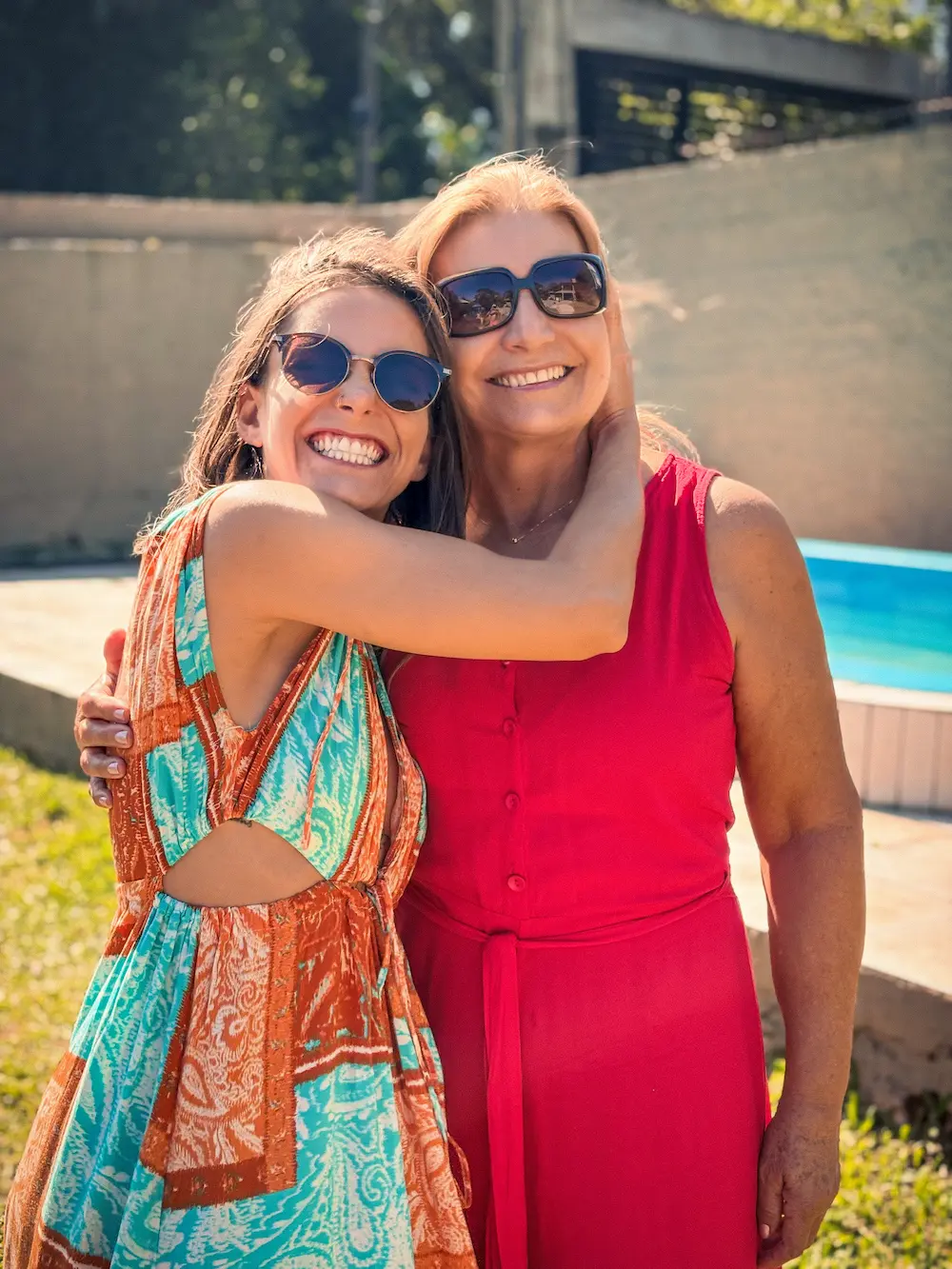 Daniella wrapped in a patterned shawl sitting in a green hammock holding a cup and looking thoughtfully to the side.