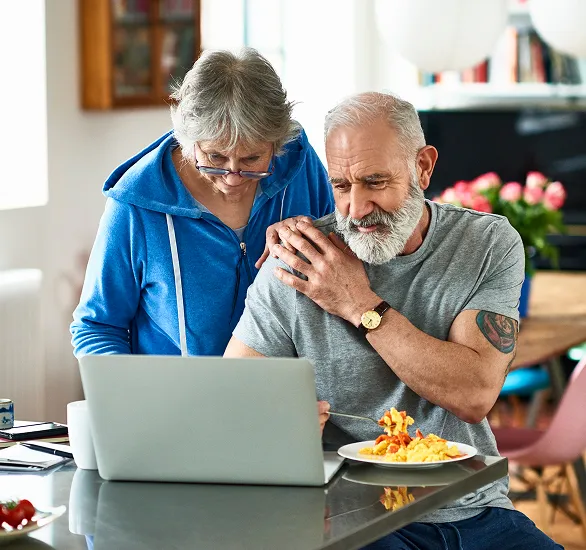 A Photograph of an elderly couple looking at a laptop computer 