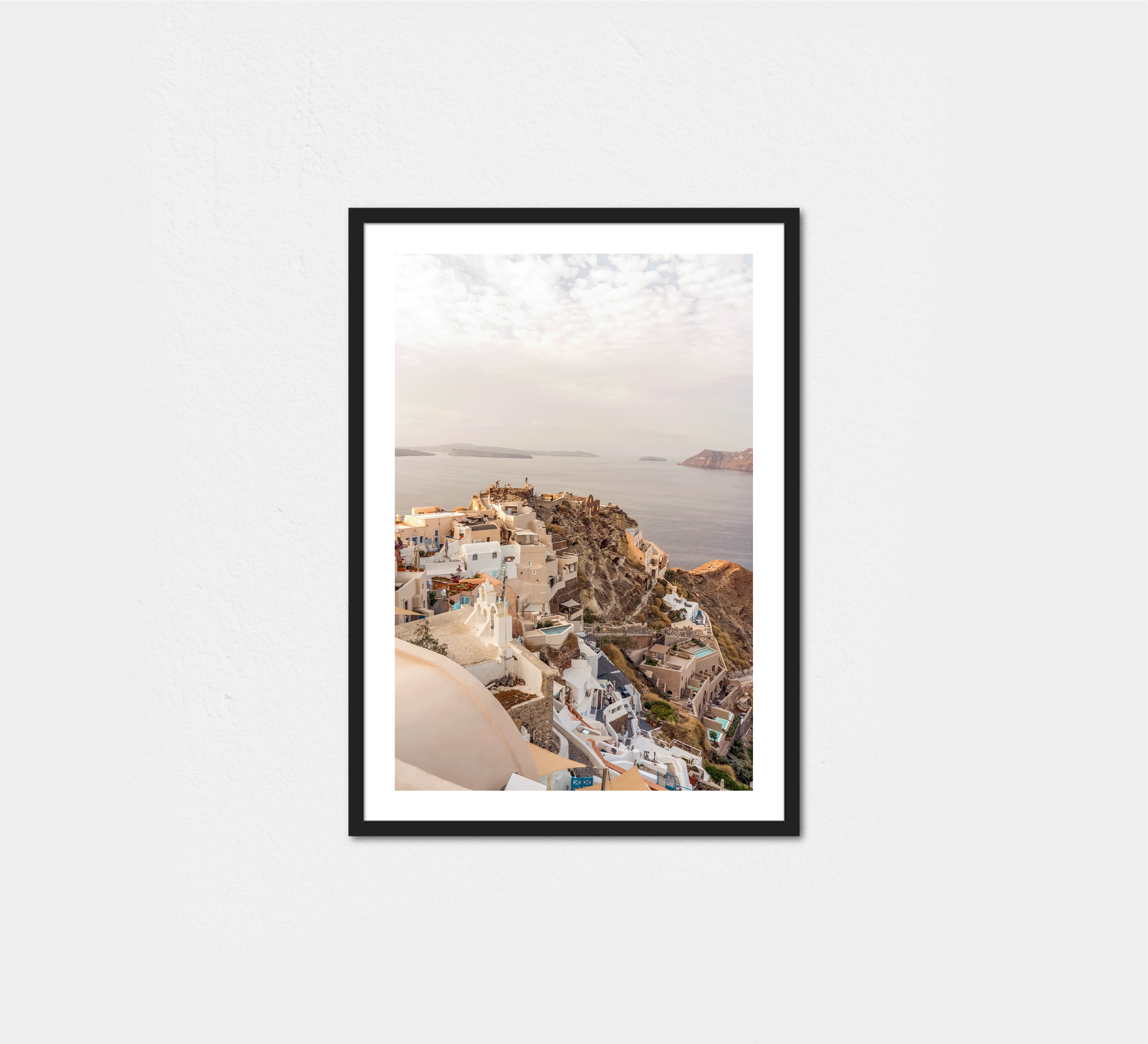 Oia village sits along Santorini's caldera edge, overlooking the Aegean Sea at golden hour.