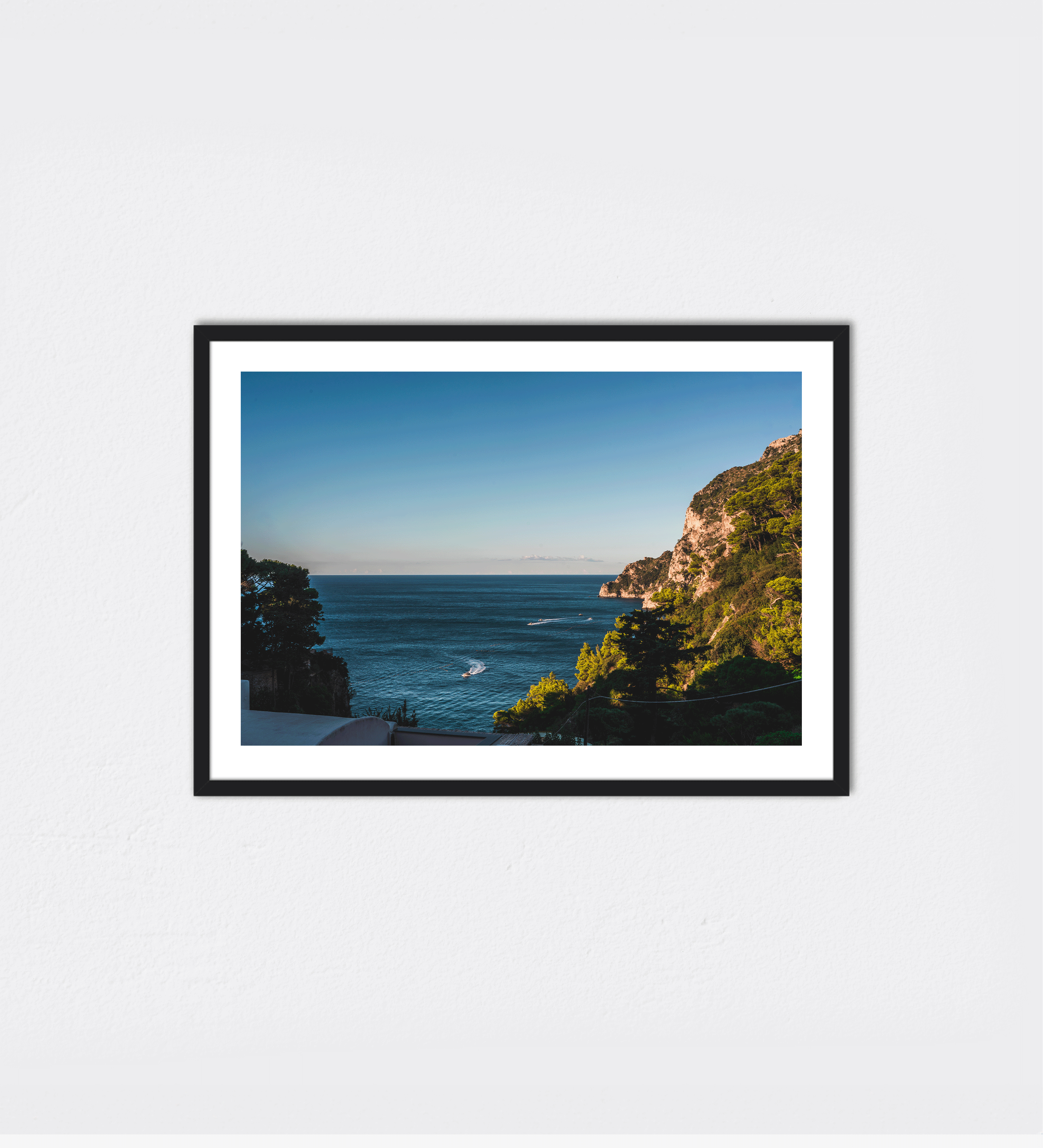 The view over Marina Piccola, where boats move across the water below. A glimpse of Capri's shoreline and the blue Mediterranean waters that surround the island.
