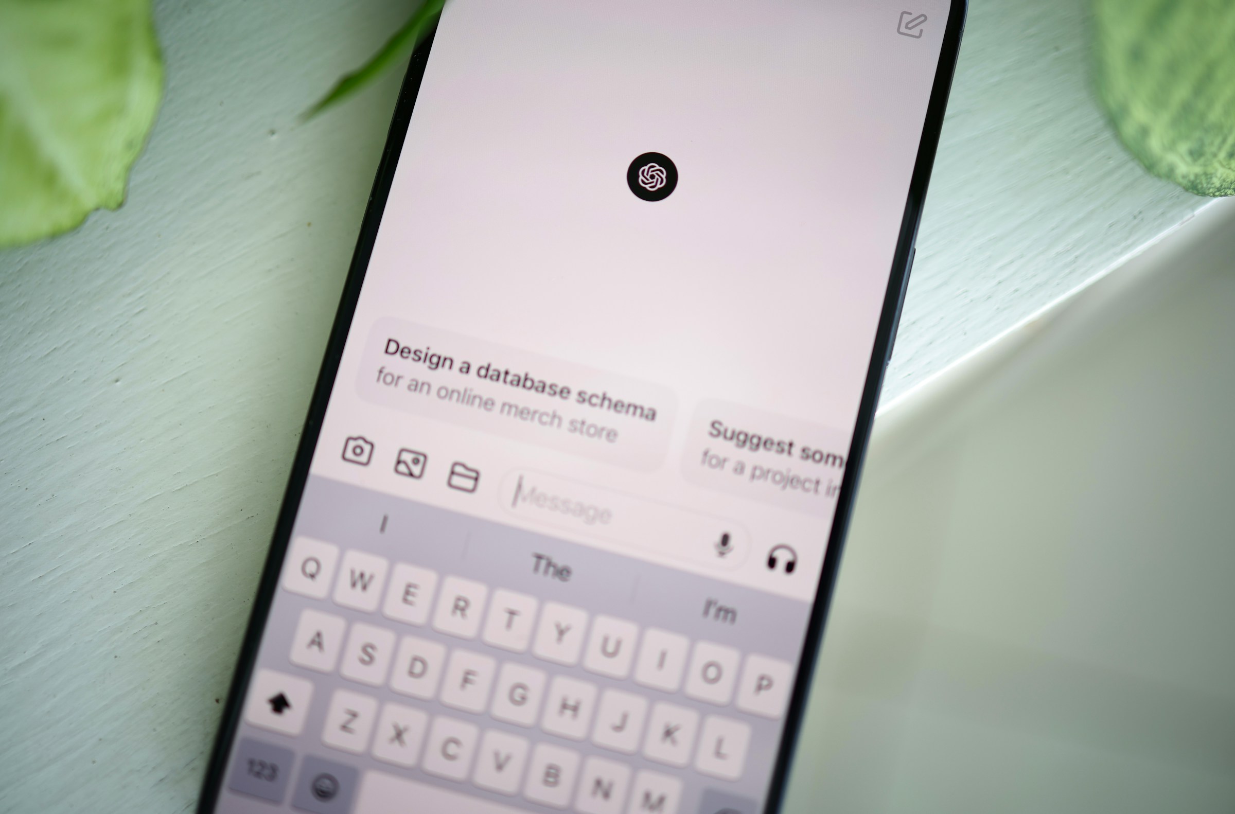 A smartphone lays on a green table, open to ChatGPT.