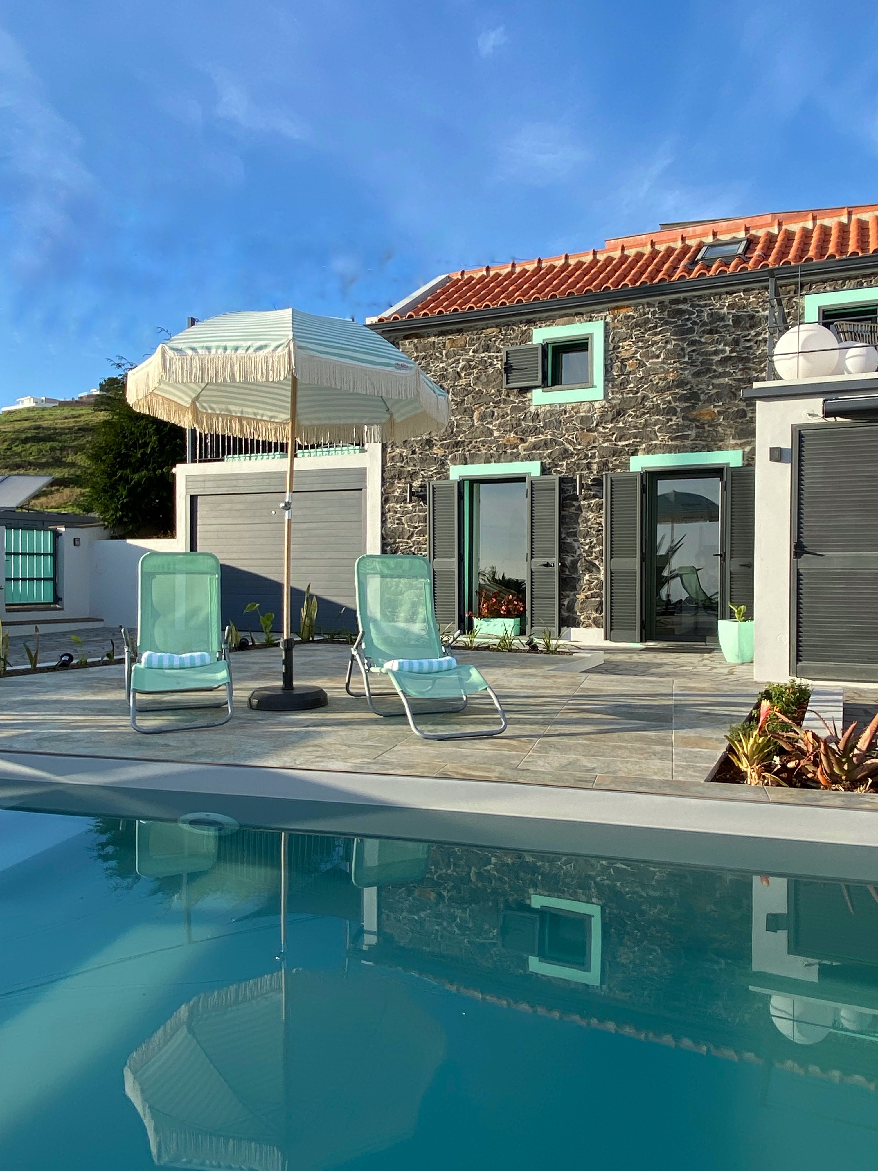 Luxury stone villa he Hideaway Madeira Private Cottage with sun loungers by the pool, featuring serene island atmosphere.