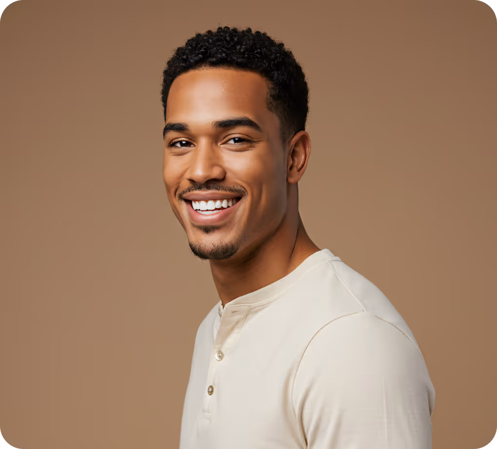 Smiling young man with short curly hair wearing a light beige henley shirt against a brown background.