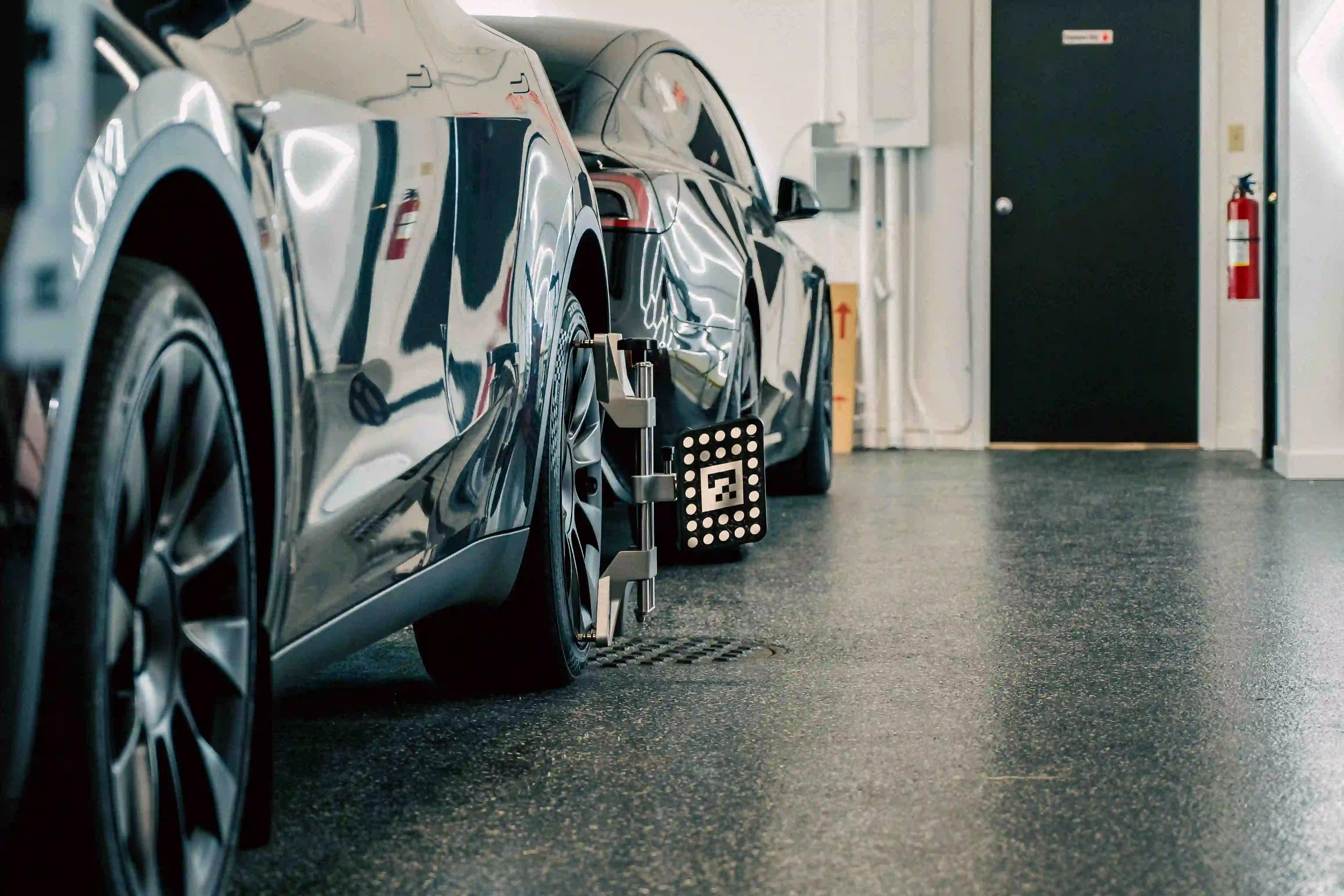 Calibration technician working on sensors at vehicle tires during alignment