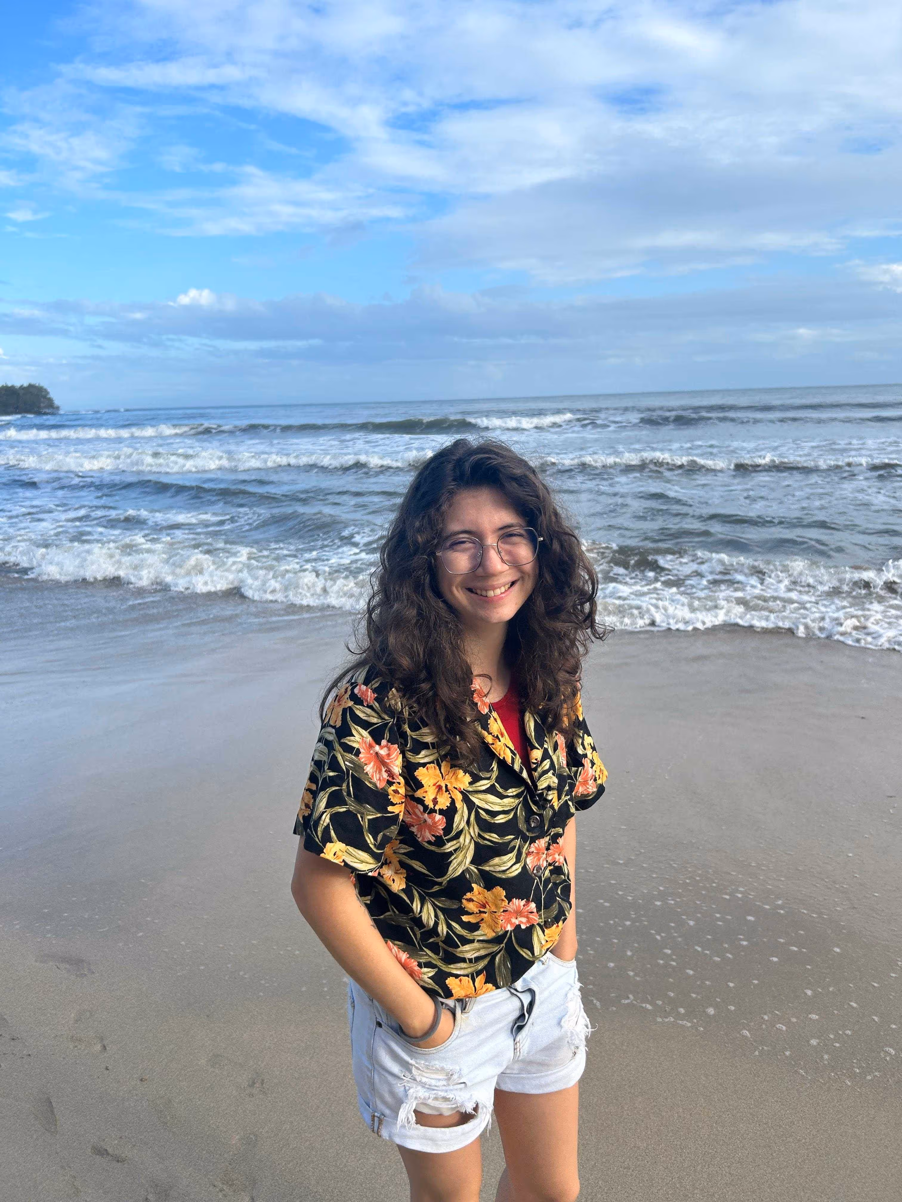 Estefanía, AI developer at CRSS, relaxing and smiling at the beach on a sunny day.