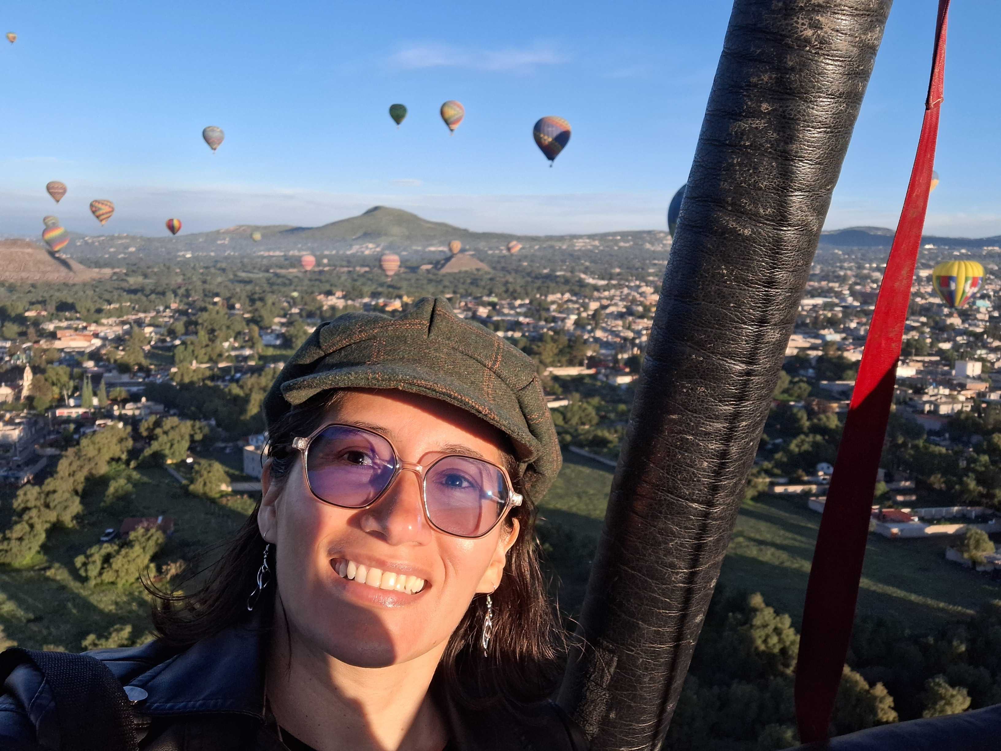 Alejandra, AI developer at CRSS, smiling while riding inside a colorful hot air balloon.