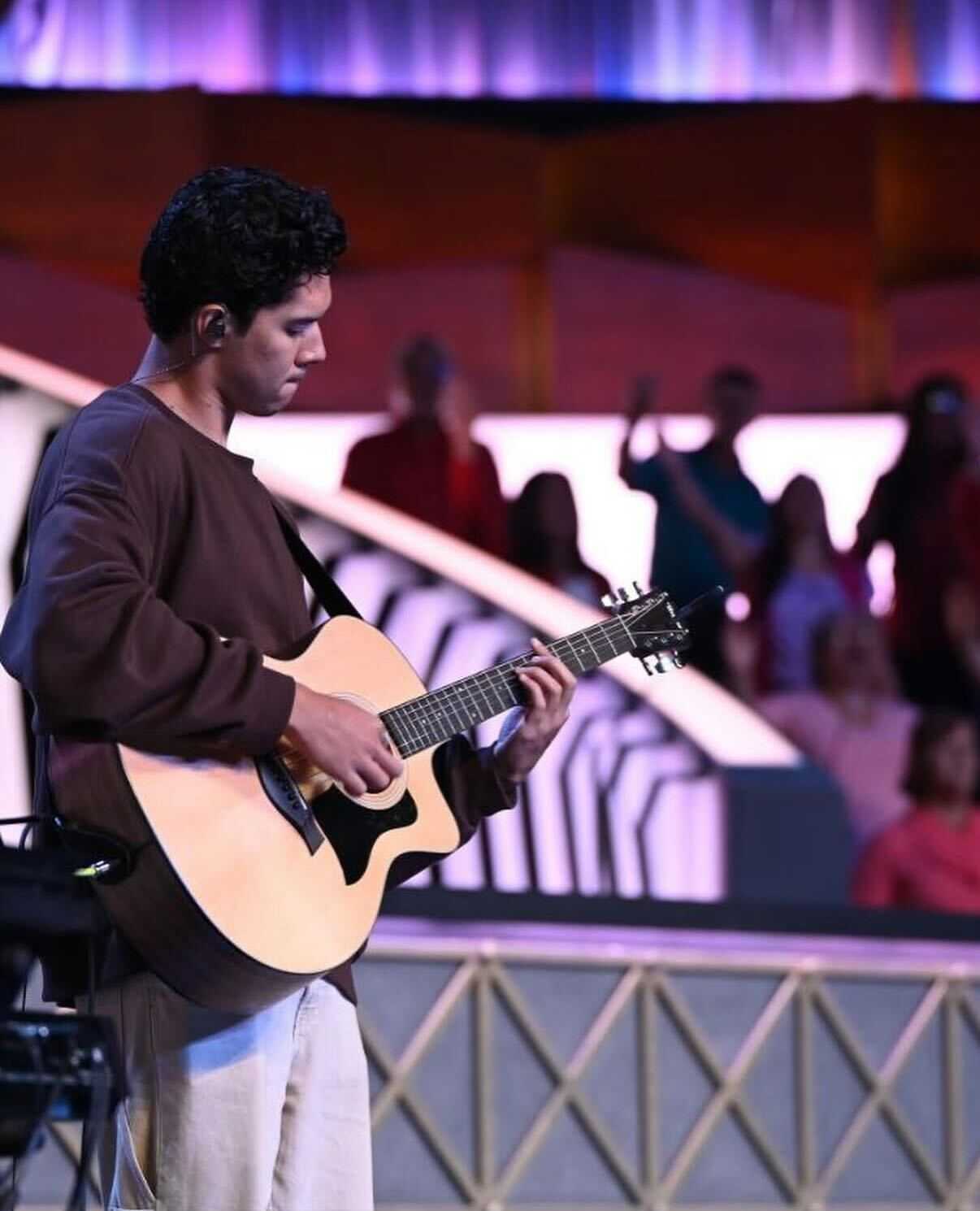 Daniel, AI developer at CRSS, playing guitar on stage during a live performance.