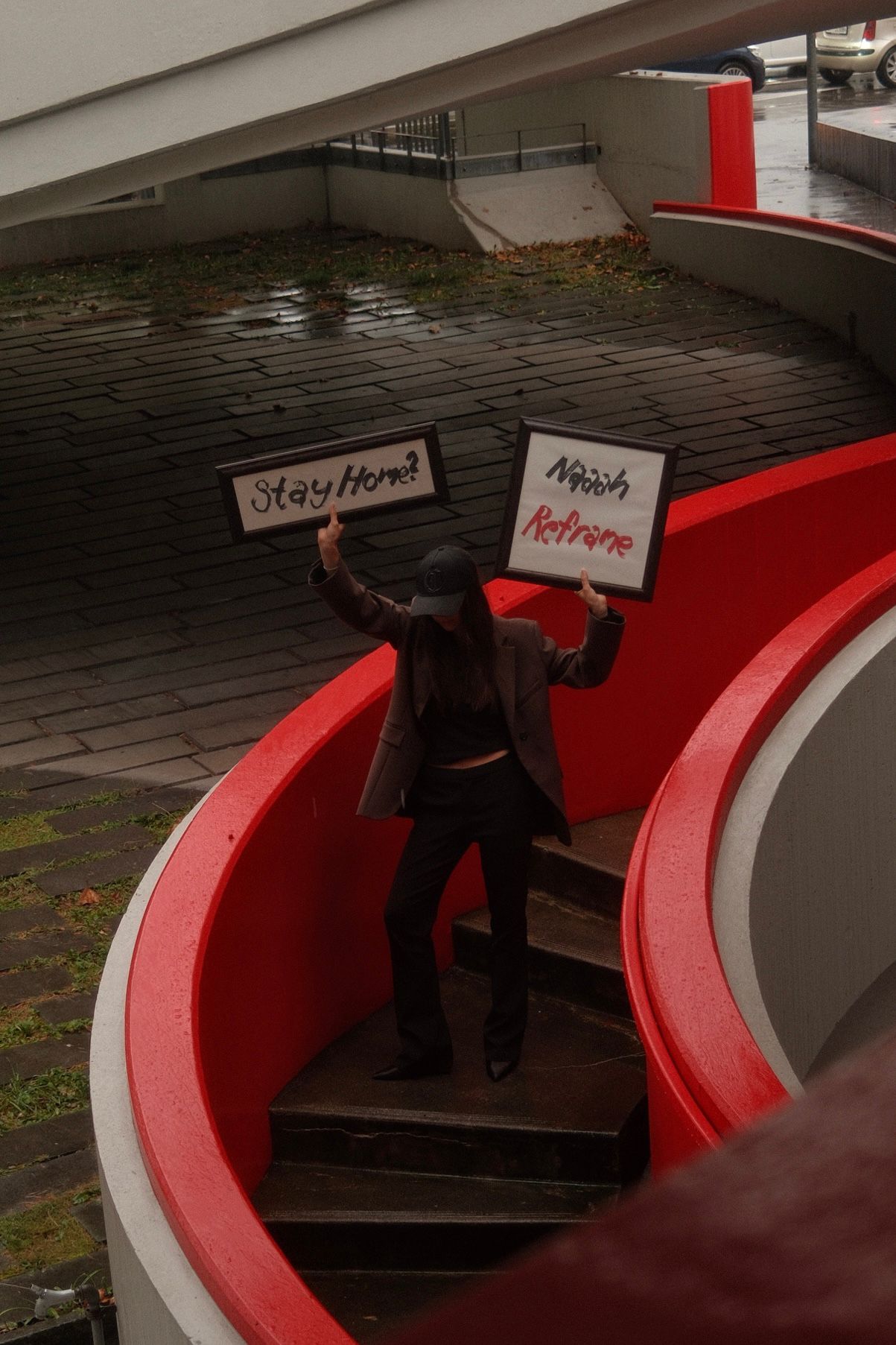 Person auf einer roten Treppe hält Schilder mit REFRAME und Eventdatum in Zürich hoch.