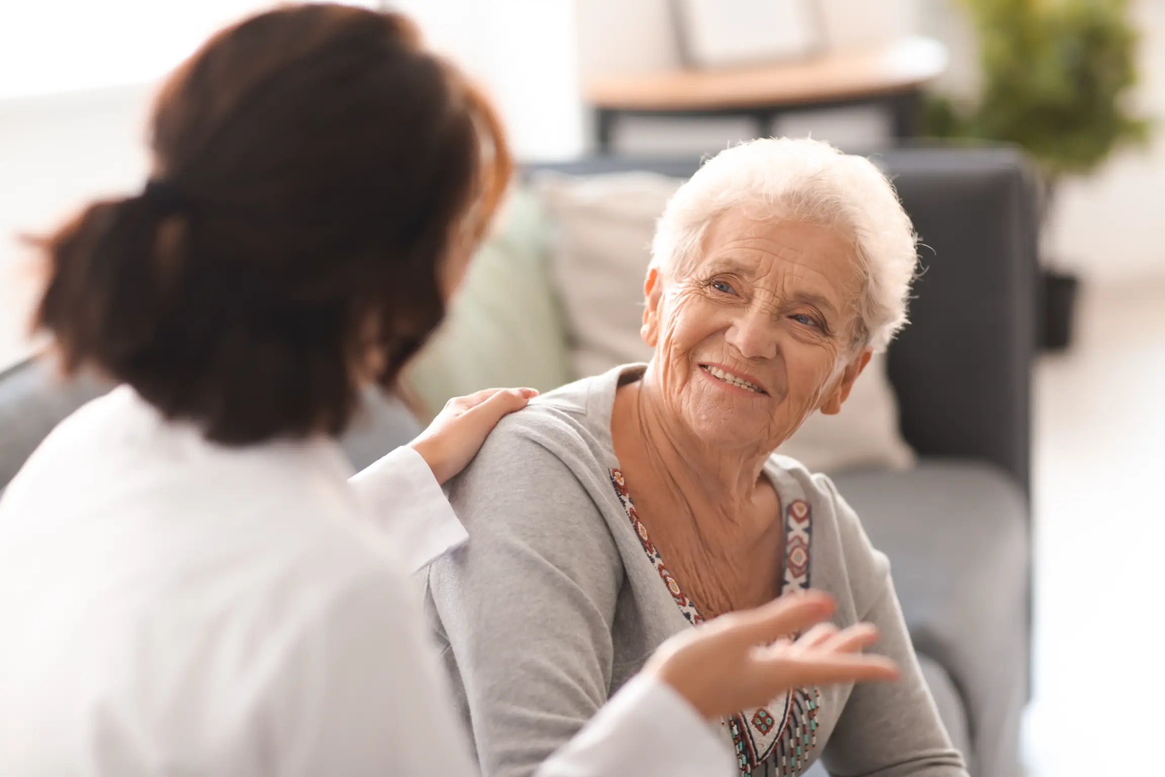 Older woman with a joyful expression talking to a healthcare provider, suggesting a friendly consultation or follow-up visit from this chiropractic clinic.
