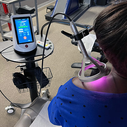 A Laser therapy device, used for pain relief and tissue healing, featuring an interactive display with a human body diagram for selecting treatment areas and a connected laser applicator.