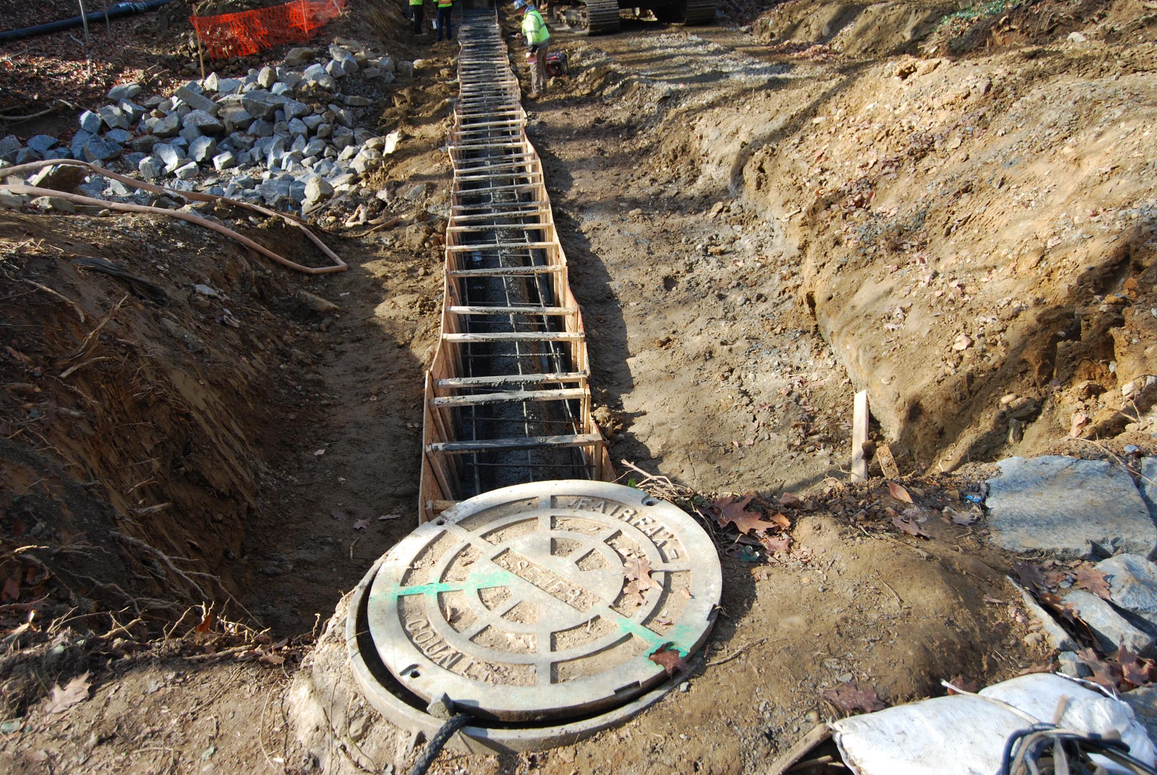 View of sewer manhole cover and a trench dug for pipes