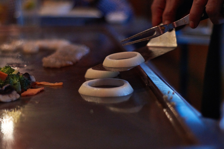 hibachi chef stacks onion rings on a grill