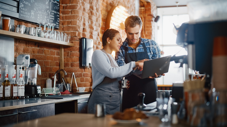 Barista and Cafe Owner Discuss Work Schedule and Menu on Laptop Computer.