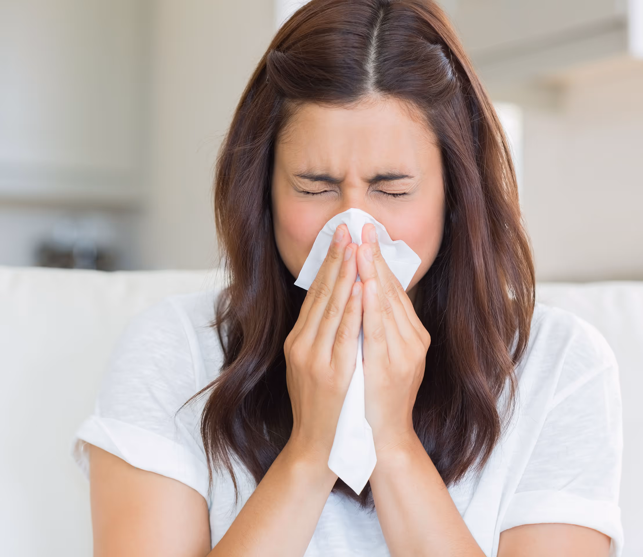woman with allergies blowing her nose 