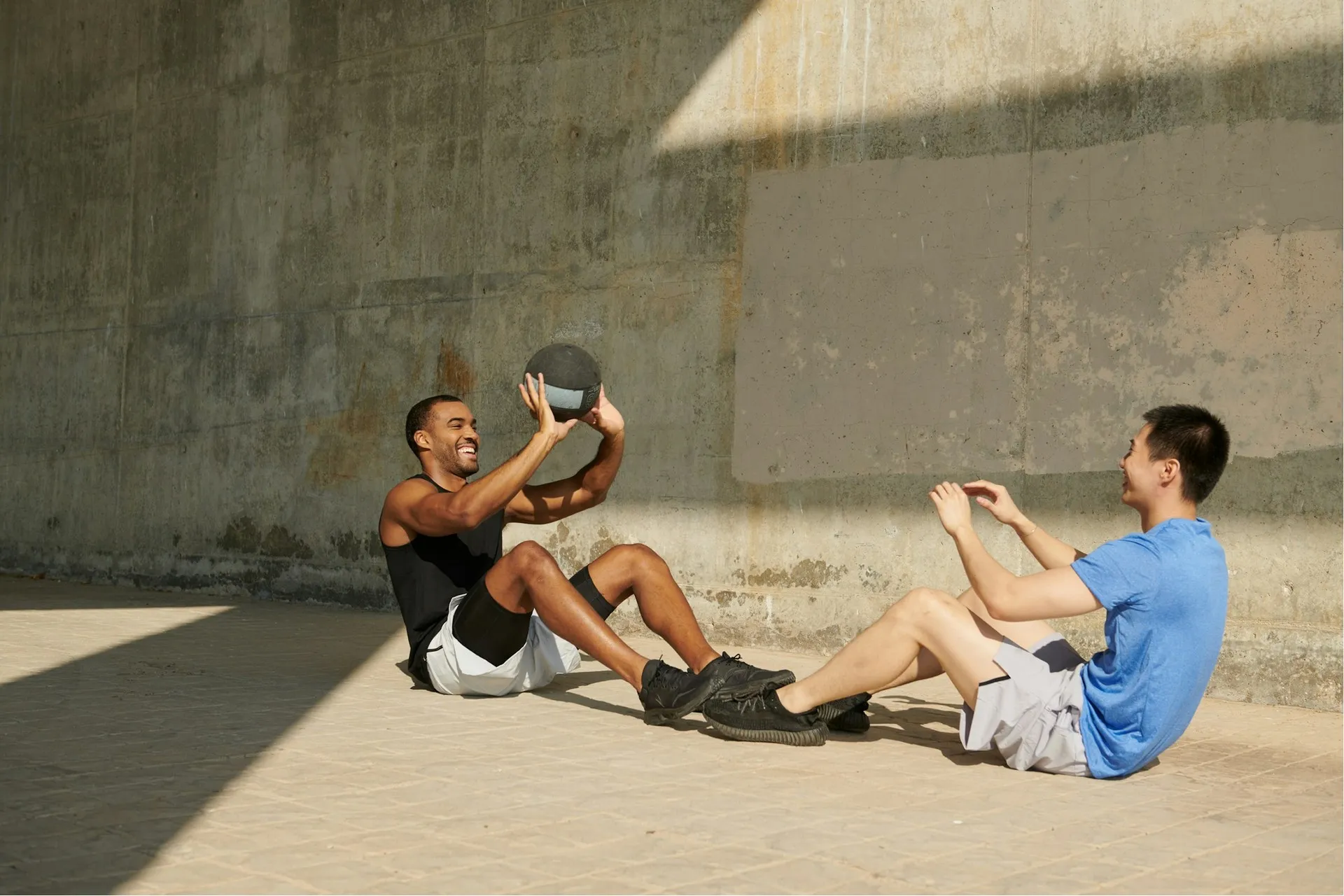 Two men doing sit-ups with a medicine ball outdoors