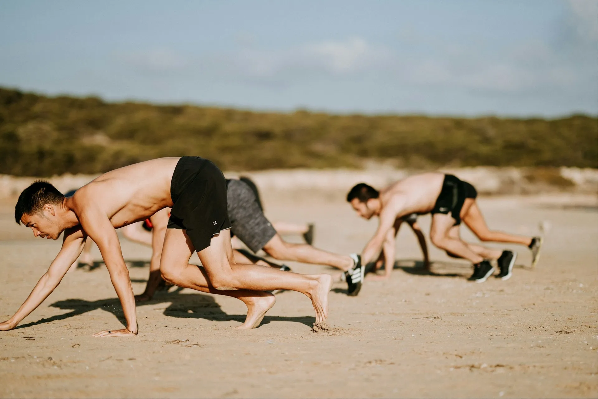 Athletes doing bear crawls during beach outdoor training