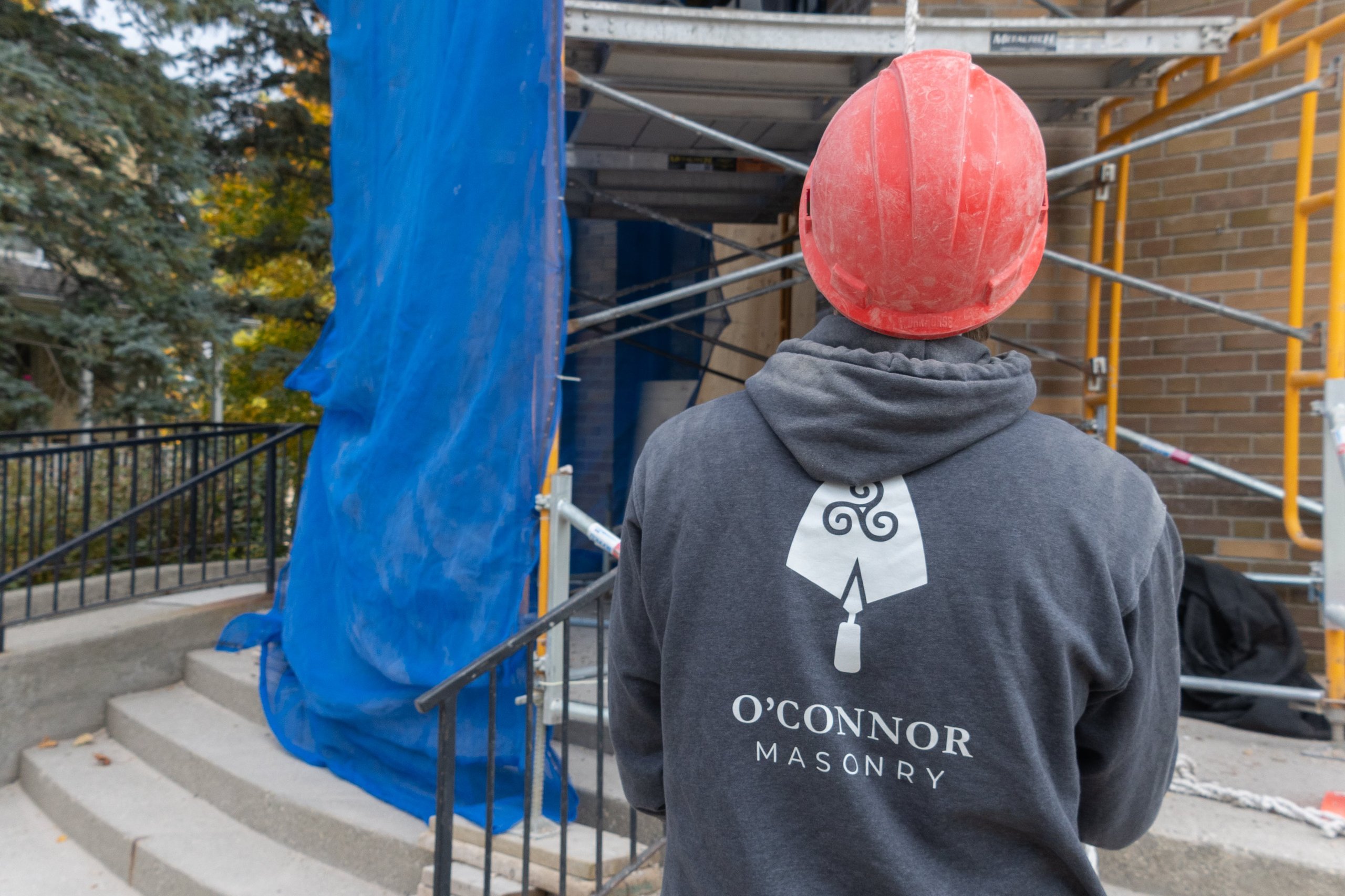 Photo of a masonry construction worker with his back facing the camera, representing ER Media’s dedication to supporting skilled trades and building strong partnerships with Ontario contractors.