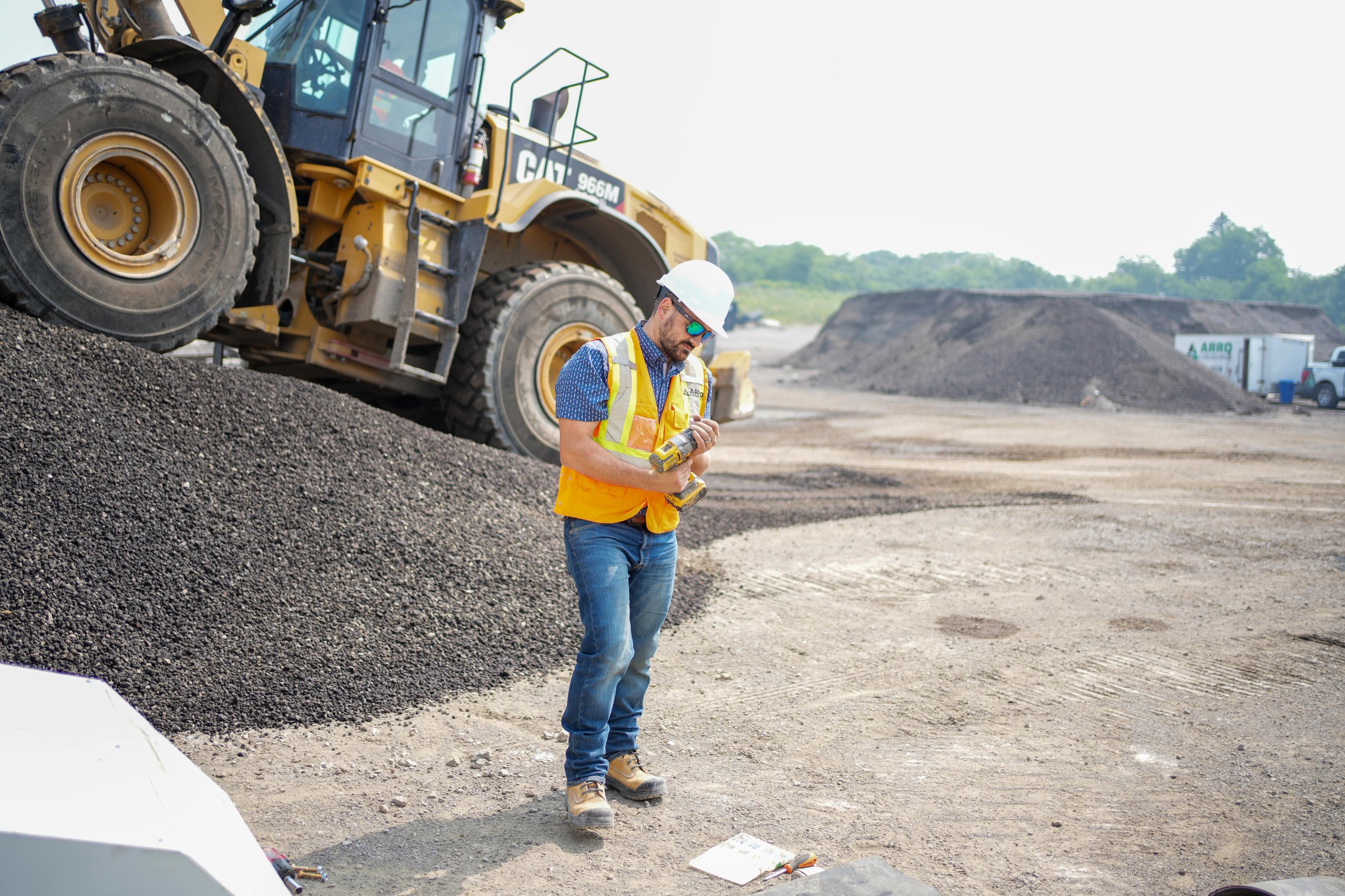 Photo of a construction company owner holding a tool with a loader in the background, representing ER Media’s close relationships with contractors and hands-on industry expertise.