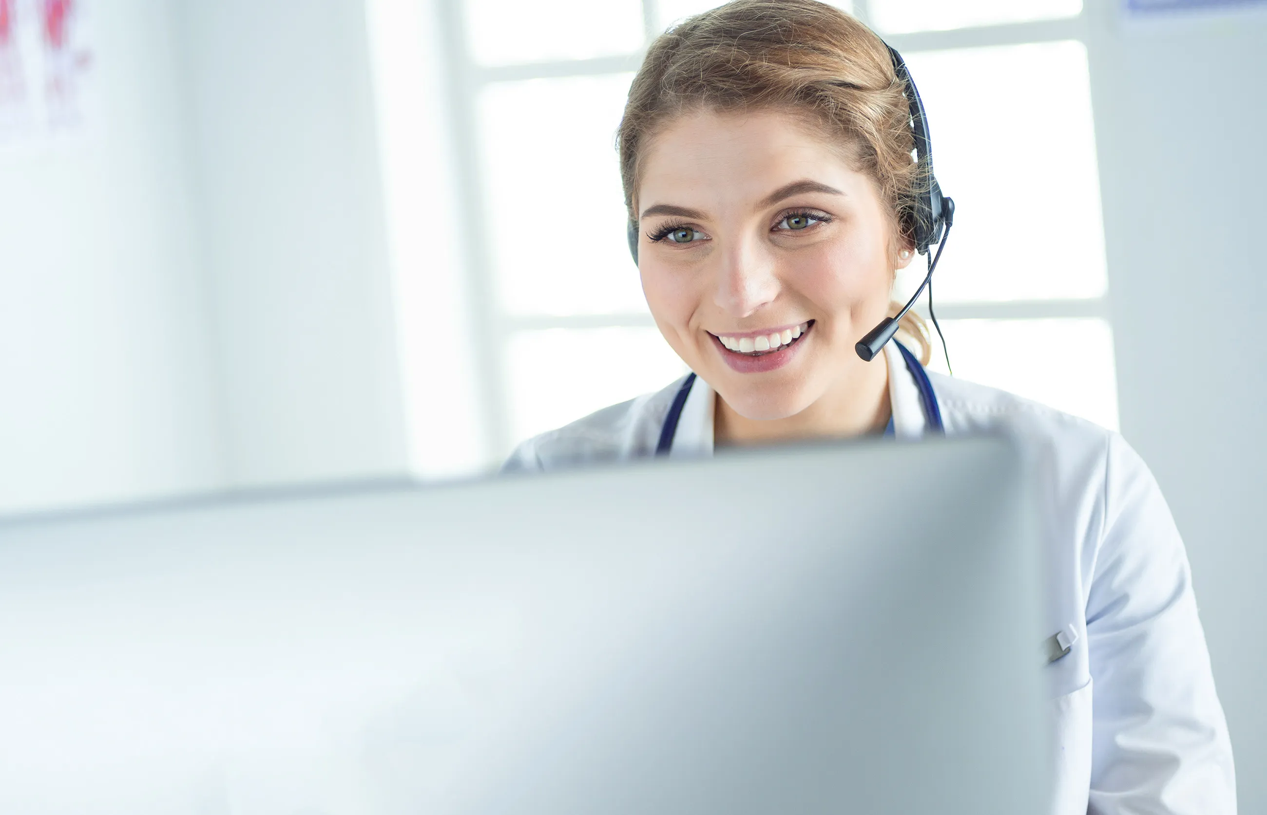Young practitioner support staff working at the clinic reception desk, answering phone calls and scheduling appointments