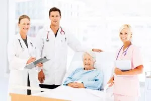 Three doctors standing next to a patient in a hospital bed