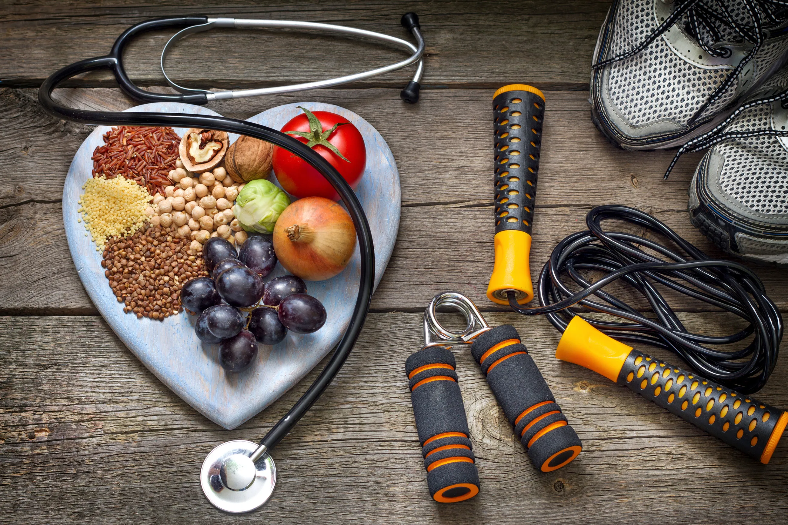 A stethoscope and workout equipment placed next to a plate of nutritious food