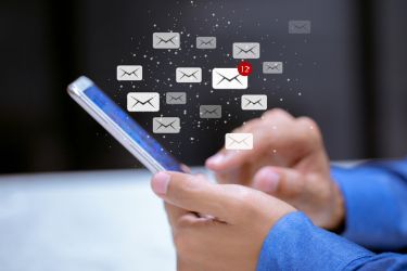 Hands holding a phone and sending emails